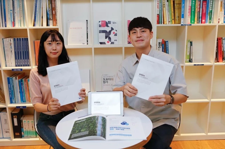 현대위아 직원들이 23일 경기도 의왕시 현대위아 의왕연구소에서 ‘현대위아 2021 지속가능성보고서’를 들어 보이고 있다. / 사진제공=현대위아