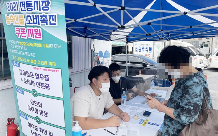 월곡시장 1번 출구에 마련된 행사 부스에서 구매영수증을 확인하고 온누리상품권을 지급하고 있는 모습.