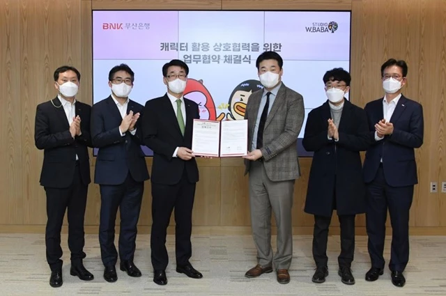 BNK부산은행은 25일(화) 오후, 부산은행 본점에서 애니메이션 제작 전문기업인 ‘스튜디오더블유바바(주)’와 캐릭터 콘텐츠 활용을 위한 업무 협약식을 체결했다고 밝혔다.(사진 왼쪽부터 부산은행 강상길 디지털금융본부장, 스튜디오더블유바바㈜ 이홍주 대표이사) / 사진제공=부산은행