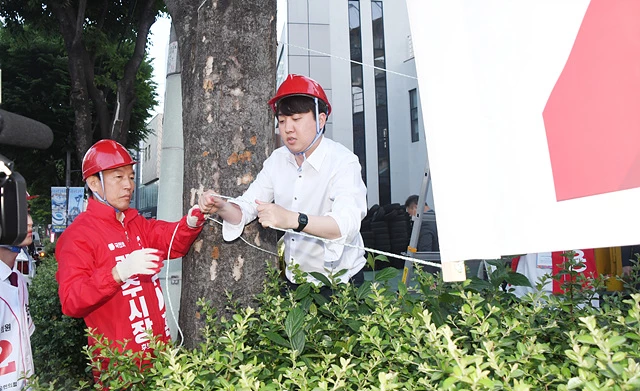 국민의힘 이준석 대표가 21일 오전 광주 북구 신안동 한 거리에서 훼손된 국민의힘 후보의 현수막을 다시 걸고 있다. 이 대표는 전날에도 광주 북구 전남대 후문에서 훼손된 현수막을 걸었지만 또 다른 훼손 사건이 벌어지자 연이틀 광주를 찾아 현수막을 게첩했다.