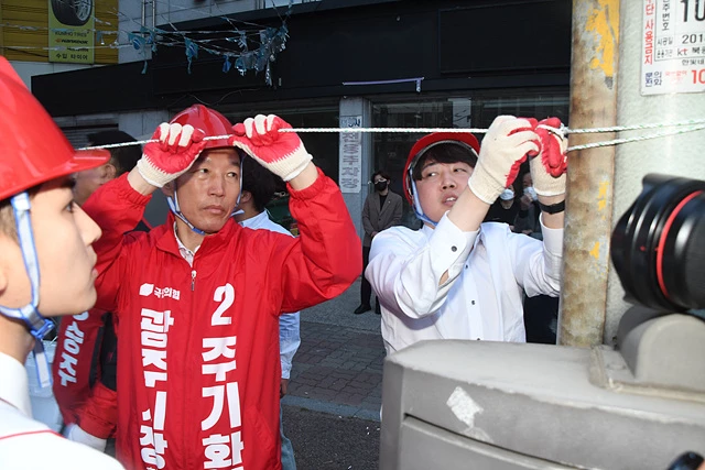 국민의힘 이준석 대표가 주기환 광주시장 후보와 함께 21일 오전 광주 북구 신안동 한 거리에서 훼손된 국민의힘 후보의 현수막을 다시 걸고 있다.