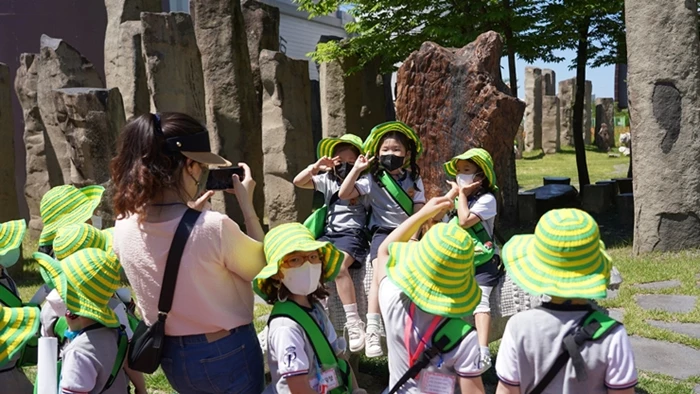 아이들이 자연사 박물관 앞 공령조각 위에 앉아 기념사진을 찍고 있다