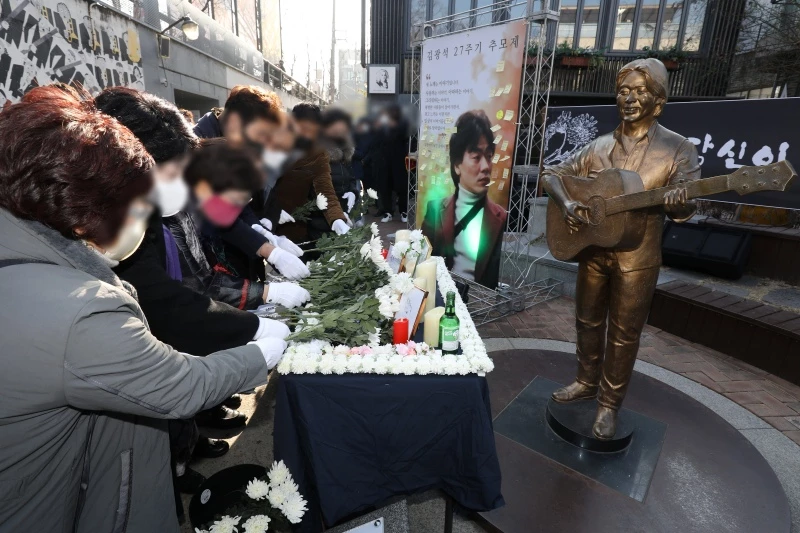 김광석 사망 27주기인 6일 오후 대구 중구 대봉동 김광석다시그리기길(김광석길)에서 열린 추모제에 참석한 시민들이 김광석 동상 앞에 헌화하고 있다. / 이하 뉴스1