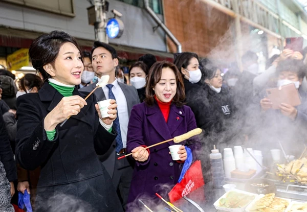 김건희 여사가 겨울철 대표 간식 어묵을 먹으면서 시민들에게 미소를 지어 보이고 있다.