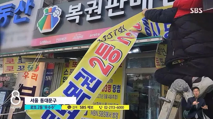로또복권 2등이 103장이나 나온 복권판매점의 주인이 ‘로또복권 2등 103명 동시 당첨’이라는 문구를 적은 현수막을 내걸고 있다. / SBS뉴스 유튜브