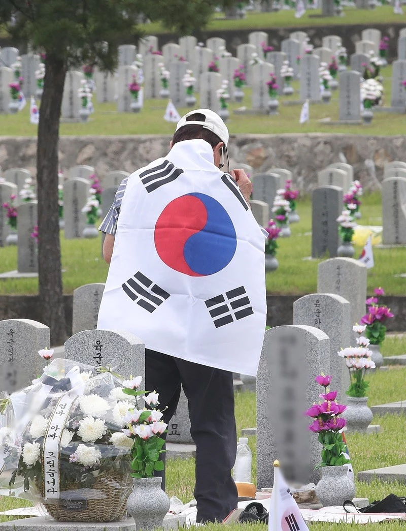 태극기를 몸에 두른 시민이 국립현충원 묘역을 참배하고 있다. / 뉴스1