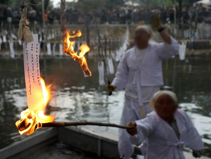 지난 27일 오후 경남 함안군 무진정에서 열린 제30회 함안낙화놀이 축제. 행사 관계자가 소원이 적힌 한지에 불을 붙이고 있다. / 뉴스1