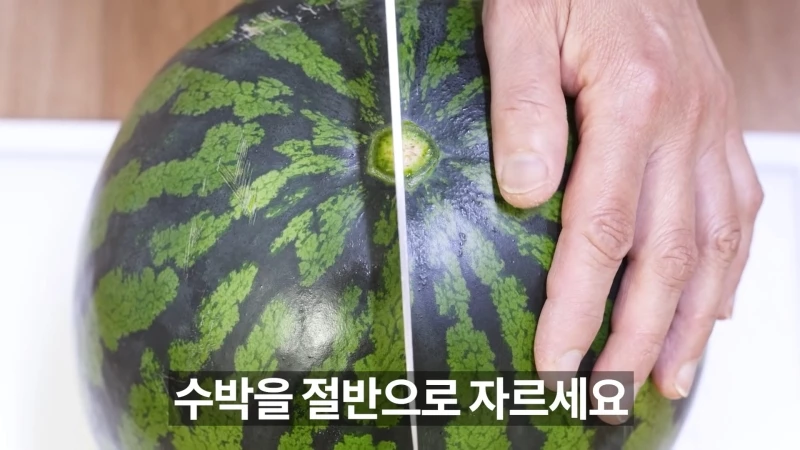 수박바 만드는 방법. 우선 꼭지를 제거한 수박을 절반으로 자른다.