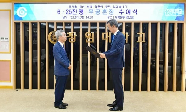 창원대 이호영 총장(오른쪽)이 대학본부에서 6·25전쟁 참전유공자인 故 문정노 선생의 아들인 문자영 창원대 R&D혁신본부장(생명보건학부 교수)에게 화랑무공훈장을 전수했다./ 사진제공=창원대