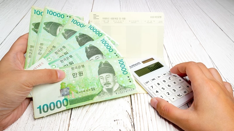 일만원권 지폐를 쥔 남성이 계산기를 누르고 있는 모습. (참고 사진) /Jessica Jeong-shutterstock.com