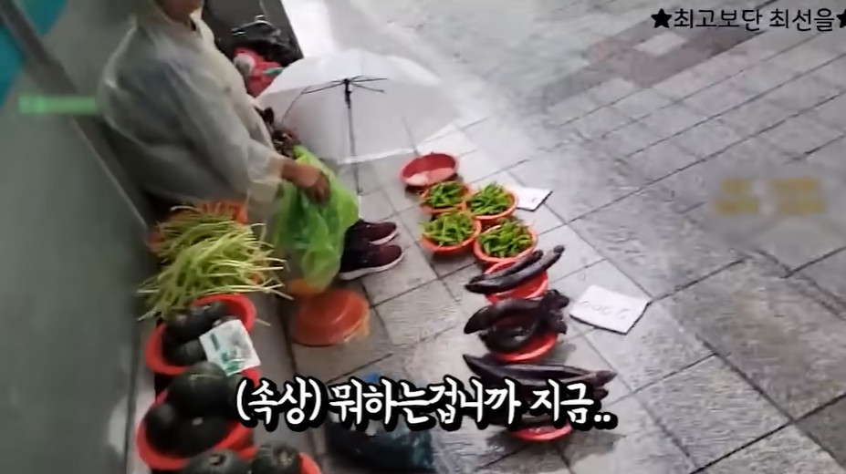 폭우 속에서 야채를 파는 할머니