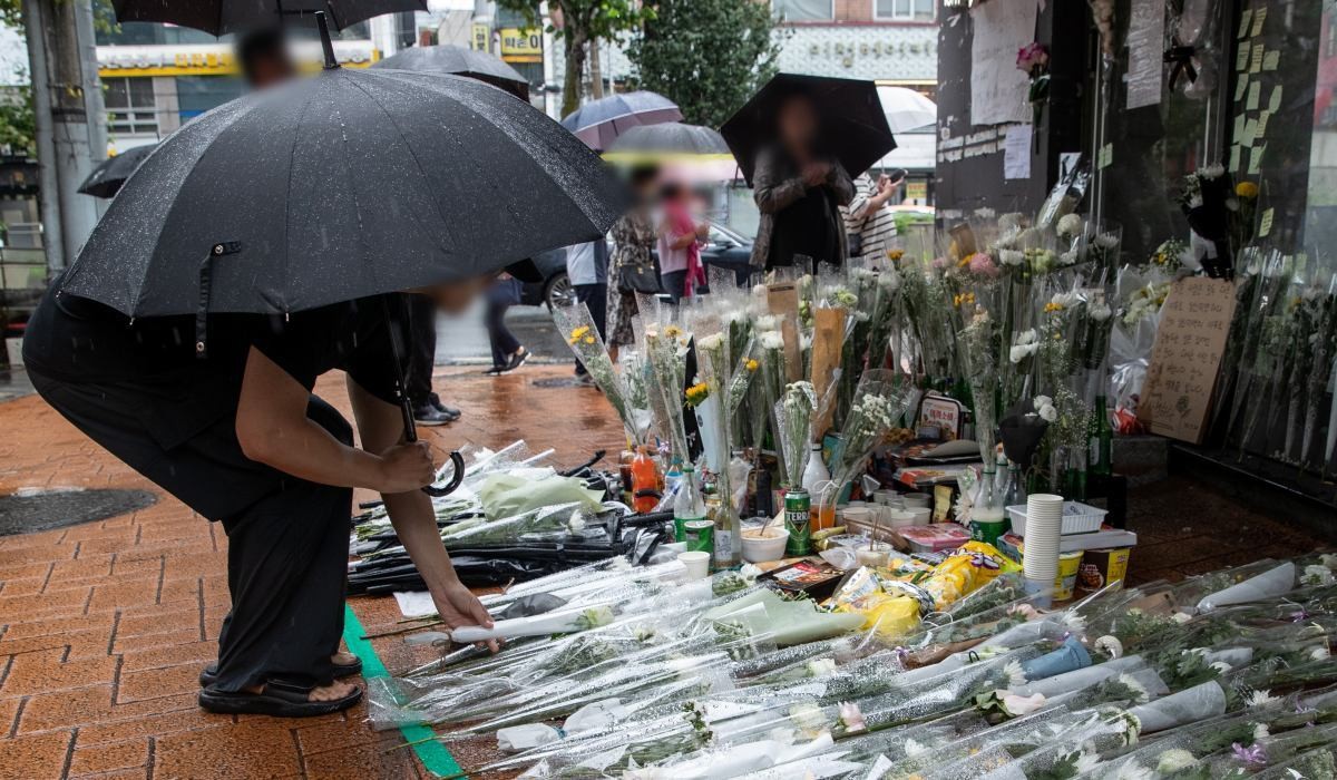 지난 23일 오전 서울 관악구 신림동 '묻지마 흉기 난동' 사건 현장을 찾은 한 시민이 조화를 내려 놓고 있다.