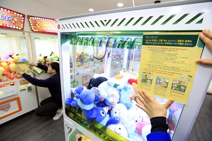 광주 북구 전남대학교 후문 인근 한 인형뽑기방에서 북구청 문화관광과 영상음반팀 직원들이 경품 종류 위반과 영업자 준수사항 위반시 처벌 홍보전단지를 부착하고 있다. / 뉴스1