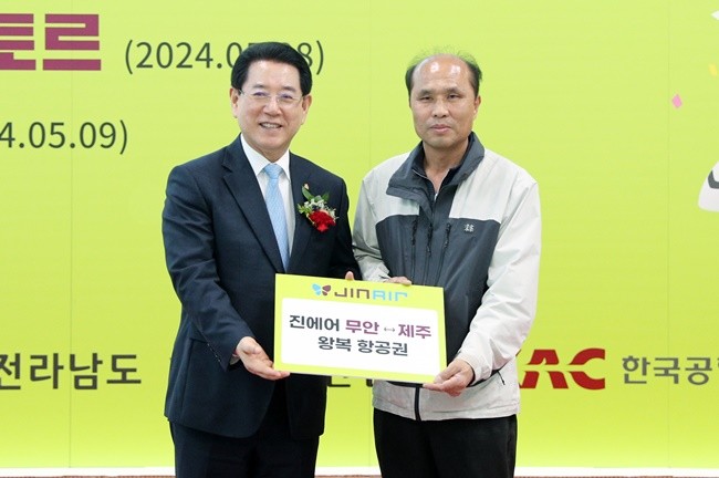 김영록 전라남도지사가 8일 무안국제공항에서 열린 ‘진에어 무안국제공항 국제선(무안-울란바토르) 취항식’에 참석, 무안-울란바토르 정기선 운항을 기념해 탑승권 첫 구매자에게 무안-제주 왕복 항공권을 증정하고 기념촬영을 하고 있다.