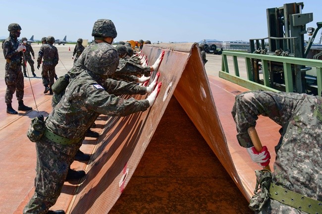 공군 제1전투비행단은 5월 9일(목) 기지 내 피해복구 훈련장에서 해군 3함대와 함께 합동 활주로 피해복구 훈련을 실시했다. 공·해 합동으로 이루어진 포설조가 접개식 유리섬유 매트(FFM: Folded Fiber glass Mat)를 이용해 폭파구를 덮고 있다. (사진 = 일병 박형준)