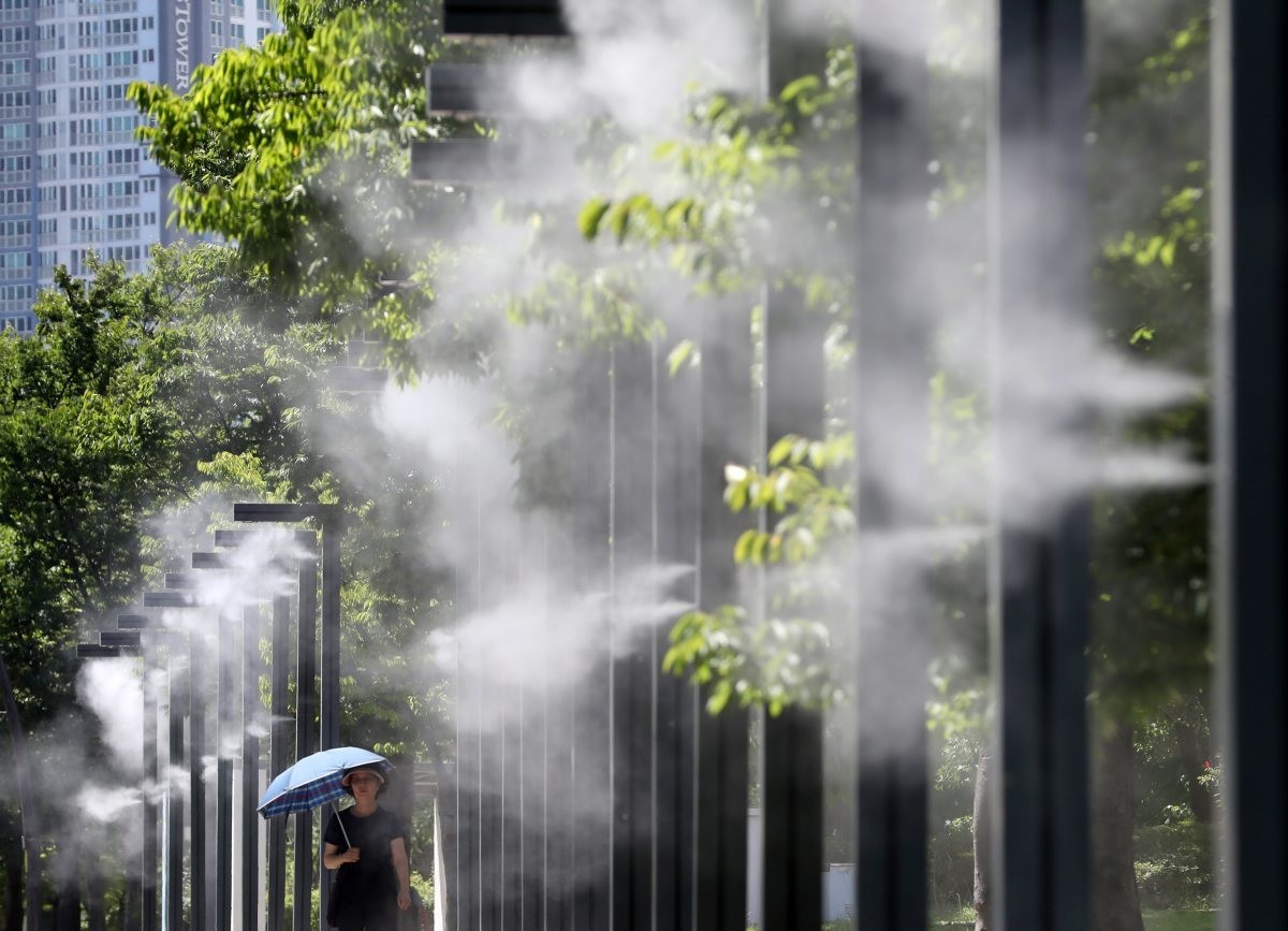 중복 더위가 기승을 부린 25일 오후 부산 부산진구 부산시민공원에서 양산을 쓴 시민이 쿨링포그를 맞으며 이동하고 있다. / 뉴스1
