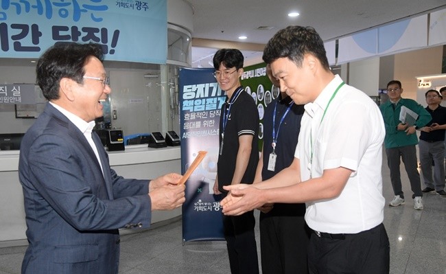 강기정 광주광역시장이 1일 오전 시청 1층 당직실에서 '당직 송별행사'에 참석해 마지막 당직 근무자들에게 당직수당이 담긴 월급봉투를 전달하고 있다. /광주광역시 제공