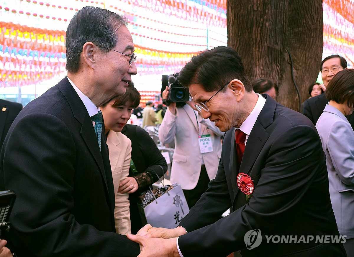 김문수 민의힘 대선 후보(오른쪽)와 한덕수 무소속 대선 예비후보가 5일 서울 종로구 조계사에서 열린 불기 2569년 부처님오신날 봉축법요식을 마친 뒤 악수하고 있다. / 연합뉴스