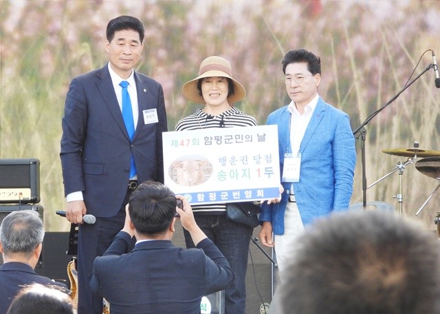 오민수 함평군번영회장(왼쪽)이 송아지를 경품으로 받은 군민(가운데)과 기념촬영을 하고 있다.있다.