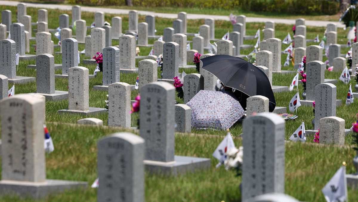 서울 동작구 국립서울현충원에서 한 시민이 묘역 앞에 앉아있다. / 연합뉴스