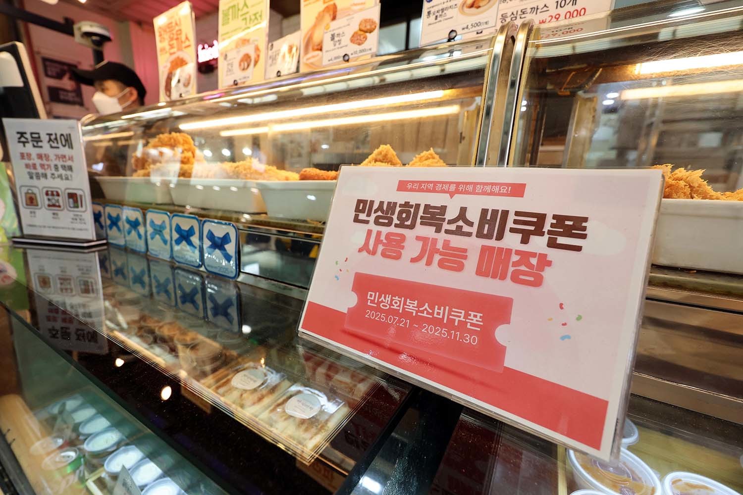 민생회복 소비쿠폰 1차 신청 첫 날인 21일 서울의 한 돈가스 전문점에 쿠폰 사용 관련 안내문이 붙어있다. / 뉴스1