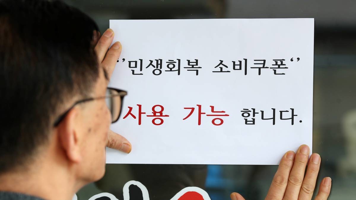 한 음식점 주인이 출입문에 민생회복 소비쿠폰 사용 가능 안내문을 붙이고 있다. / 뉴스1