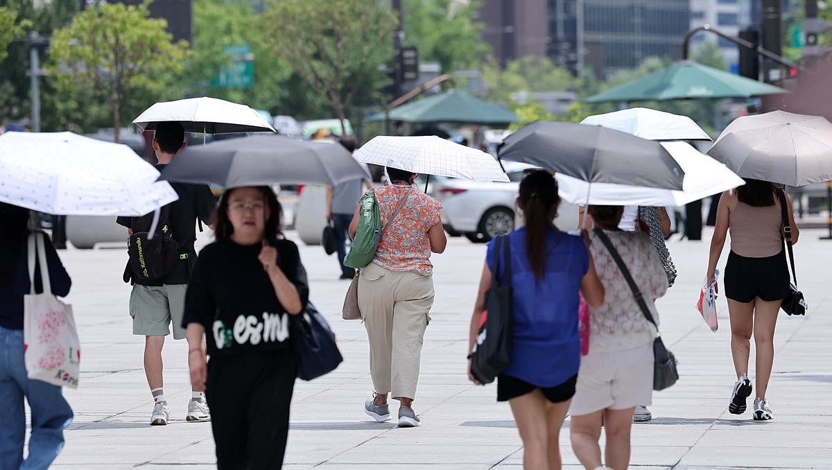 전국적으로 무더위가 계속되고 있는 가운데 서울 종로구 광화문광장에서 시민들이 양산을 쓴 채 발걸음을 옮기고 있는 모습 / 뉴스1