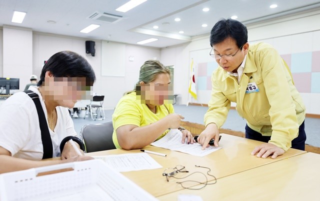 지난달 21일 현장 점검 차 수완동 행정복지센터에 마련된 민생회복 소비쿠폰 신청 창구를 방문한 박병규 광산구청장이 시민의 신청서 작성을 돕고 있다.