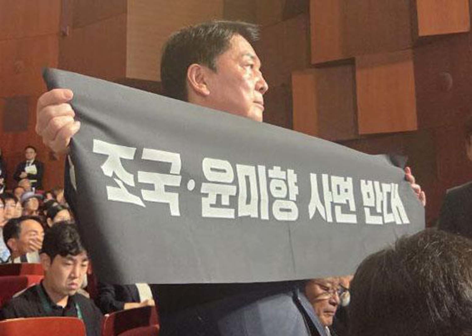 안철수 국민의힘 당대표 후보가 15일 오전 서울 종로구 세종문화회관에서 열린 제80주년 광복절 경축식에 참석해 경축사 중인 이재명 대통령을 향해 조국 전 조국혁신당 대표와 윤미향 전 의원의 사면 반대 플래카드를 들어보이며 항의하고 있다. / 안 후보 캠프 제공