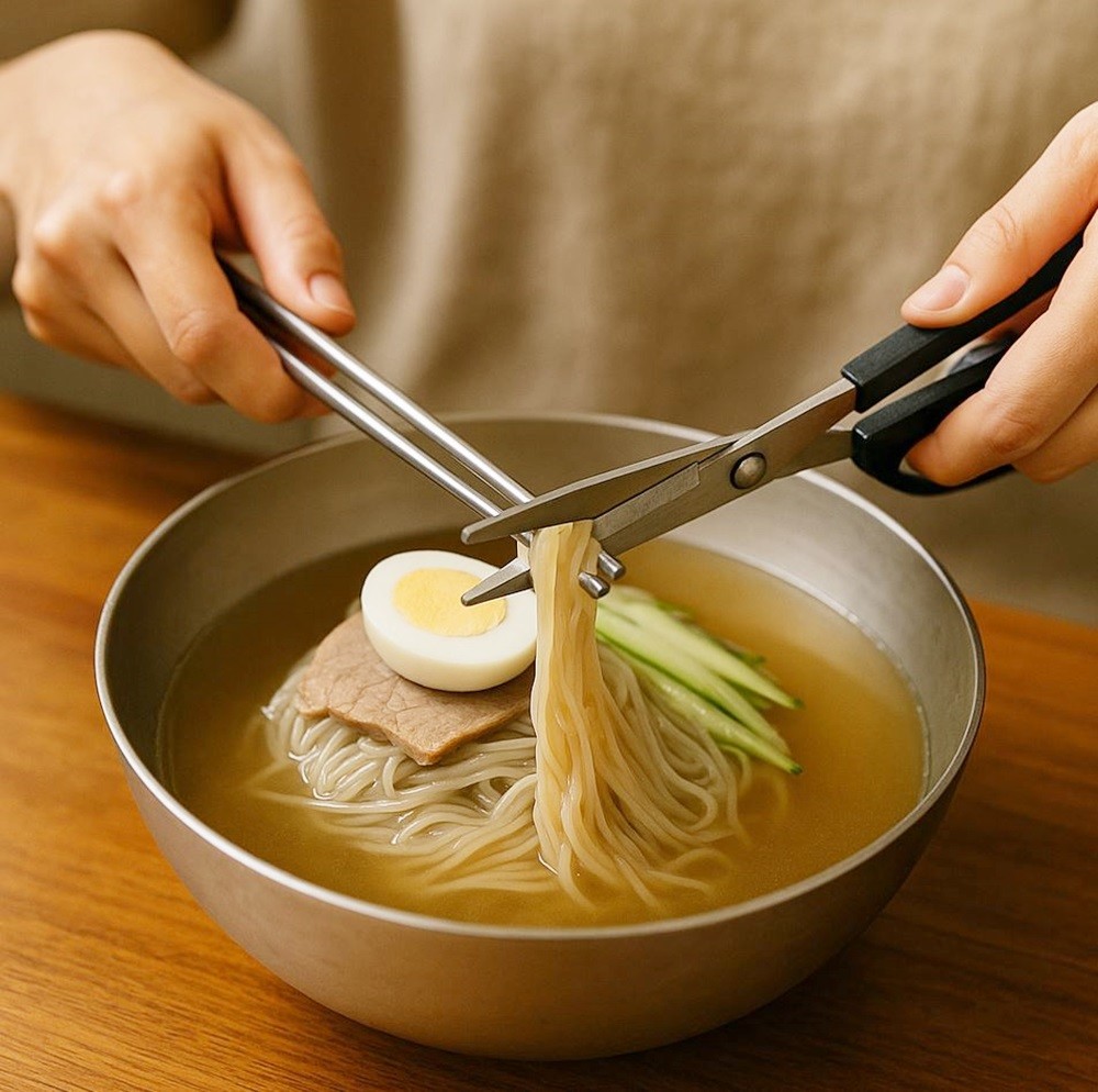여름철 별미 평양냉면을 가위로 자르는 모습. 기사 이해를 돕기 위해 AI를 활용해 제작한 이미지입니다. 실제 모습과 다소 차이가 있을 수 있습니다.