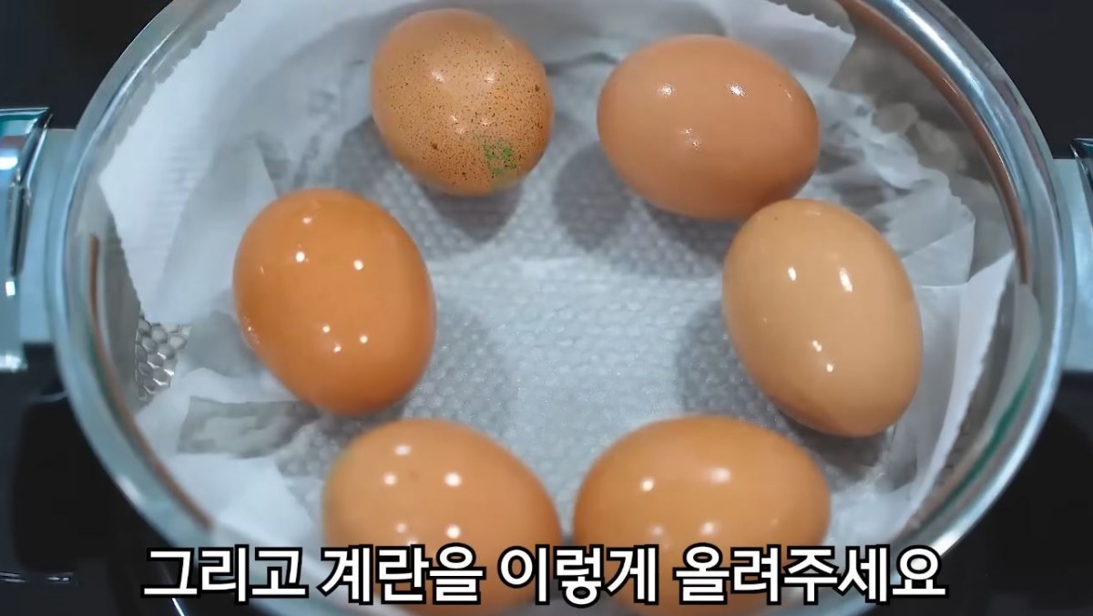 유튜버 '함께요리 맛나요리'가 키친타월을 깔고 물 한 큰술을 넣은 다음에 그 위에 계란을 올리는 모습. / 유튜브 '함께해요 맛나요리'