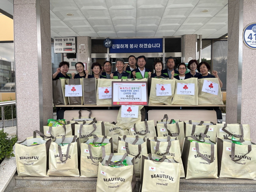 경산시 와촌면지역사회보장협의체 위원들이 11일 총 240만원 상당의 식료품 꾸러미와 함께 와촌면행정복지센터를 방문 후 기념촬영을 하고 있다. / 경산시 제공