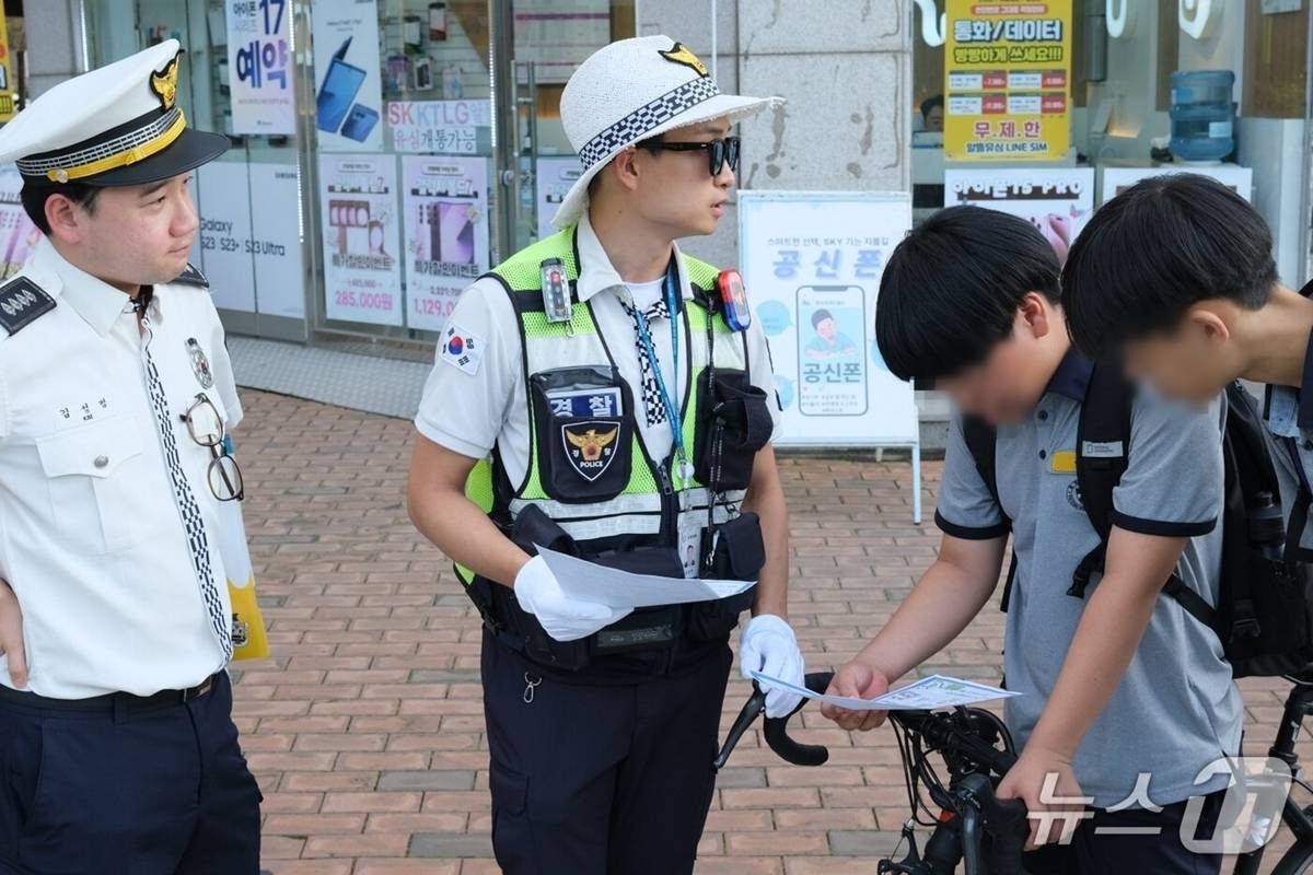 지난 15일 오후 서울 강동구 고덕역 인근에서 김성현 강동경찰서 교통안전계 경장이 나눠준 안내문을 아이들이 유심히 읽어보고 있다 / 뉴스1