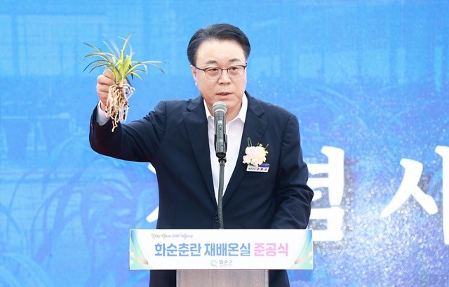 화순춘란 재배 온실 축사 중에 화순에서 키운 중국 수출용 난을 들고나와 설명하는 구복규 화순군수