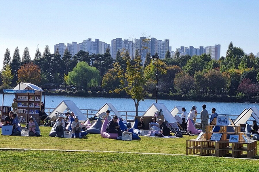 호숫가 잔디밭 야외도서관에서 책을 읽는 시민들(2024 고양 독서대전)