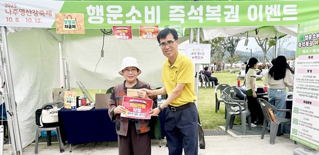 ‘2025 나주영산강축제’ 기간 동안 진행 중인 ‘행운소비 즉석복권 이벤트’ 첫 100만 원 당첨 주인공 김옥자 씨(왼쪽)가 당첨 기념사진을 찍고 있다.