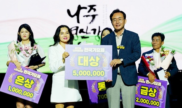 윤병태 시장(오른쪽)이 ‘제17회 나주 영산강 전국 가요제’에서 대상을 수상한 장성희 씨에게 상금 500만 원을 전달하고 기념사진을 찍고 있다.