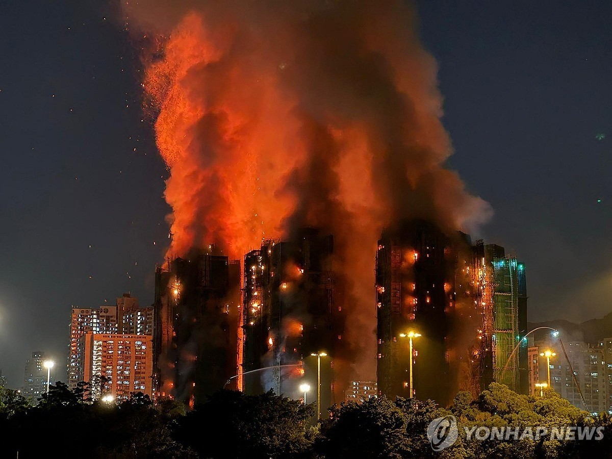 26일 오후 홍콩 북부 타이포 구역의 고층 주거단지에서 불이 나 일대에 붉은 연기가 번지고 있다. / AP 연합뉴스