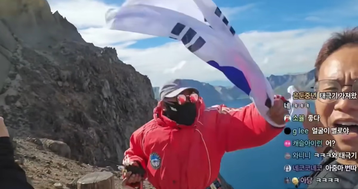 백두산 천지에서 태극기 휘날리는 유튜버의 태극기를 낚아채는 중국 공안. / 유튜브 채널 '시수기릿'