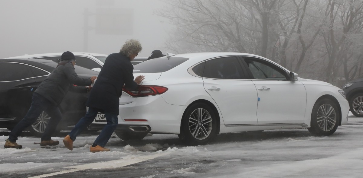 빙판길에 미끄러지는 차량을 시민들이 함께 밀고 있다. / 뉴스1