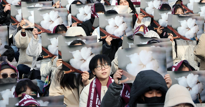 동덕여대 재학생들과 참석자들이 지난 3월 서울 안국역 인근에서 재단 규탄 집회를 열고 학교 측의 학생 대상 고소 철회를 촉구하며 목화꽃이 그려진 손팻말을 들고 있다. 목화꽃은 동덕여대의 교화다. / 뉴스1