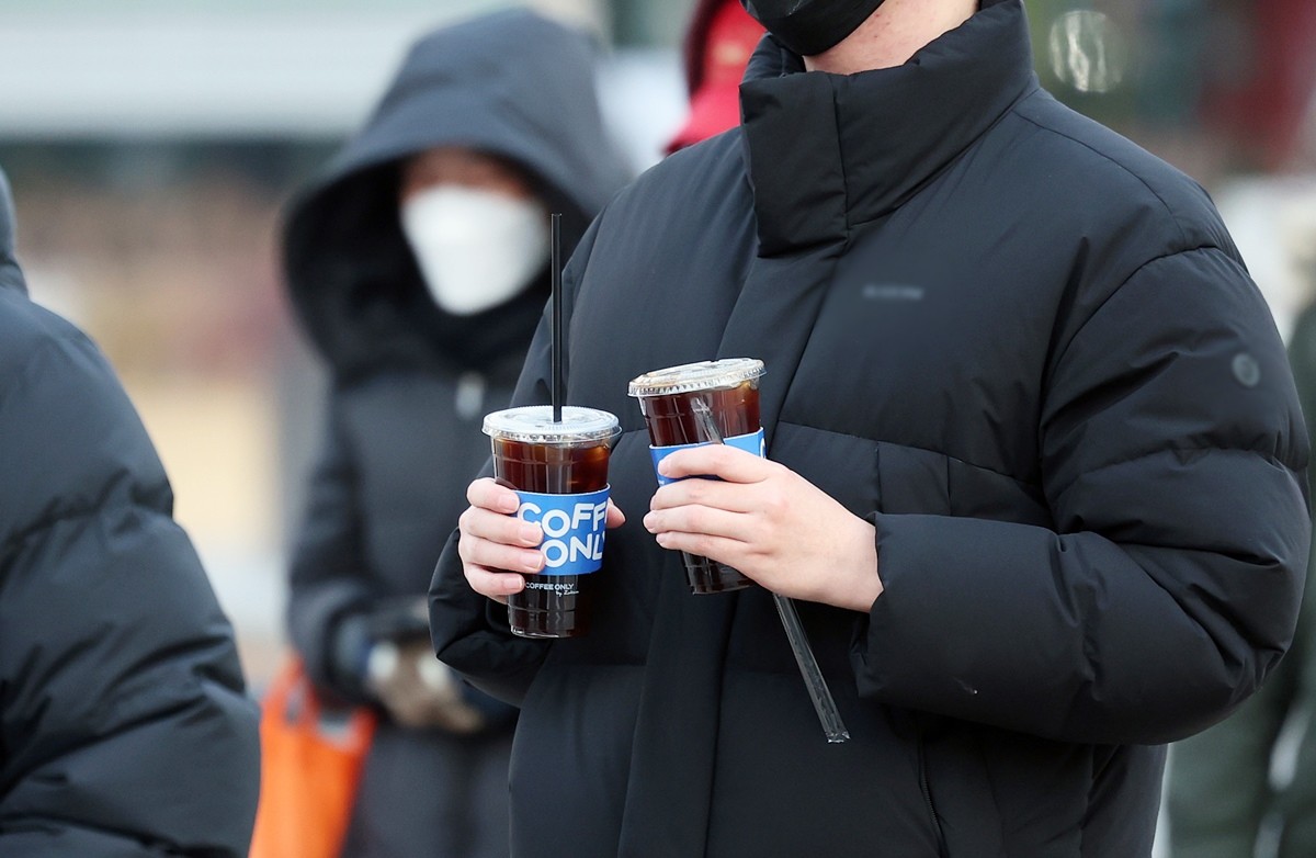 겨울철 두터운 옷차림을 한 시민이 차가운 음료를 들고 발걸음을 옮기고 있다. 기사 이해를 돕기 위한 자료 사진 / 뉴스1
