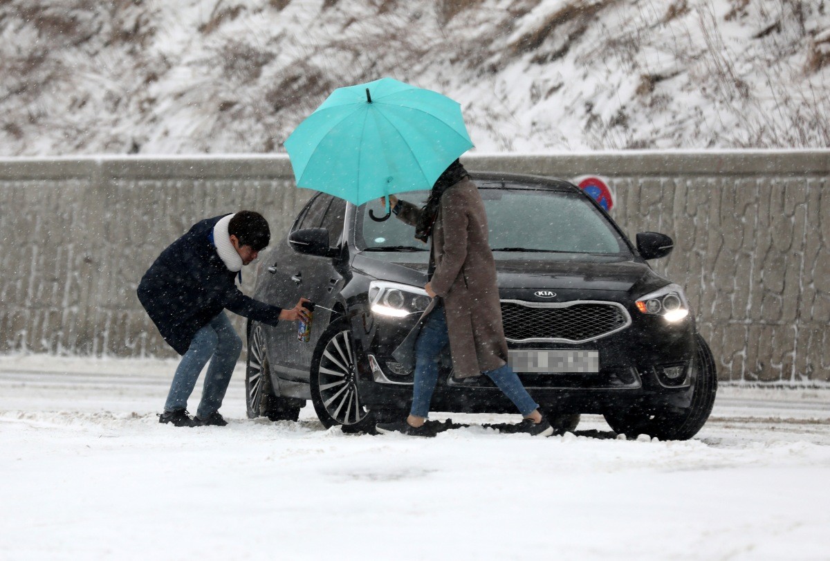근 도로가 내린 눈 때문에 미끄러워지자 운전자가 차량 바퀴에 스프레이 체인을 사용하고 있다 / 뉴스1