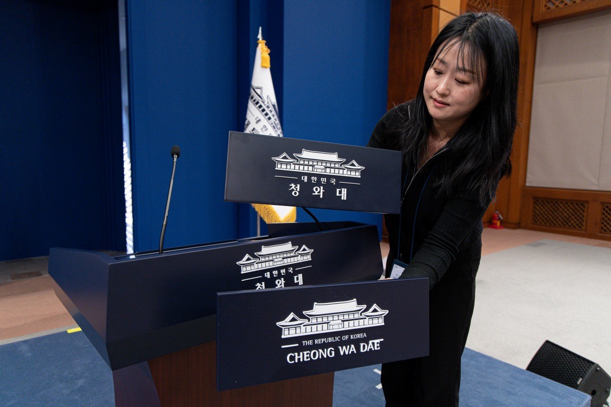 대통령실이 청와대 순차 이전을 진행 중인 지난 21일 청와대 춘추관 브리핑룸에서 직원이 탈부착 업무표장을 설치하고 있다. / 뉴스1