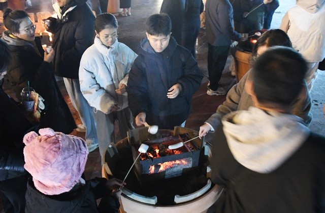 함평겨울빛축제장을 방문한 가족 단위 관광객들이 함평엑스공원 잔디밭에 마련된 DJ와 함께하는 불멍 토크쇼에서 마시멜로를 구워 먹으로 겨울 축제의 낭만을 만끽하고 있다.