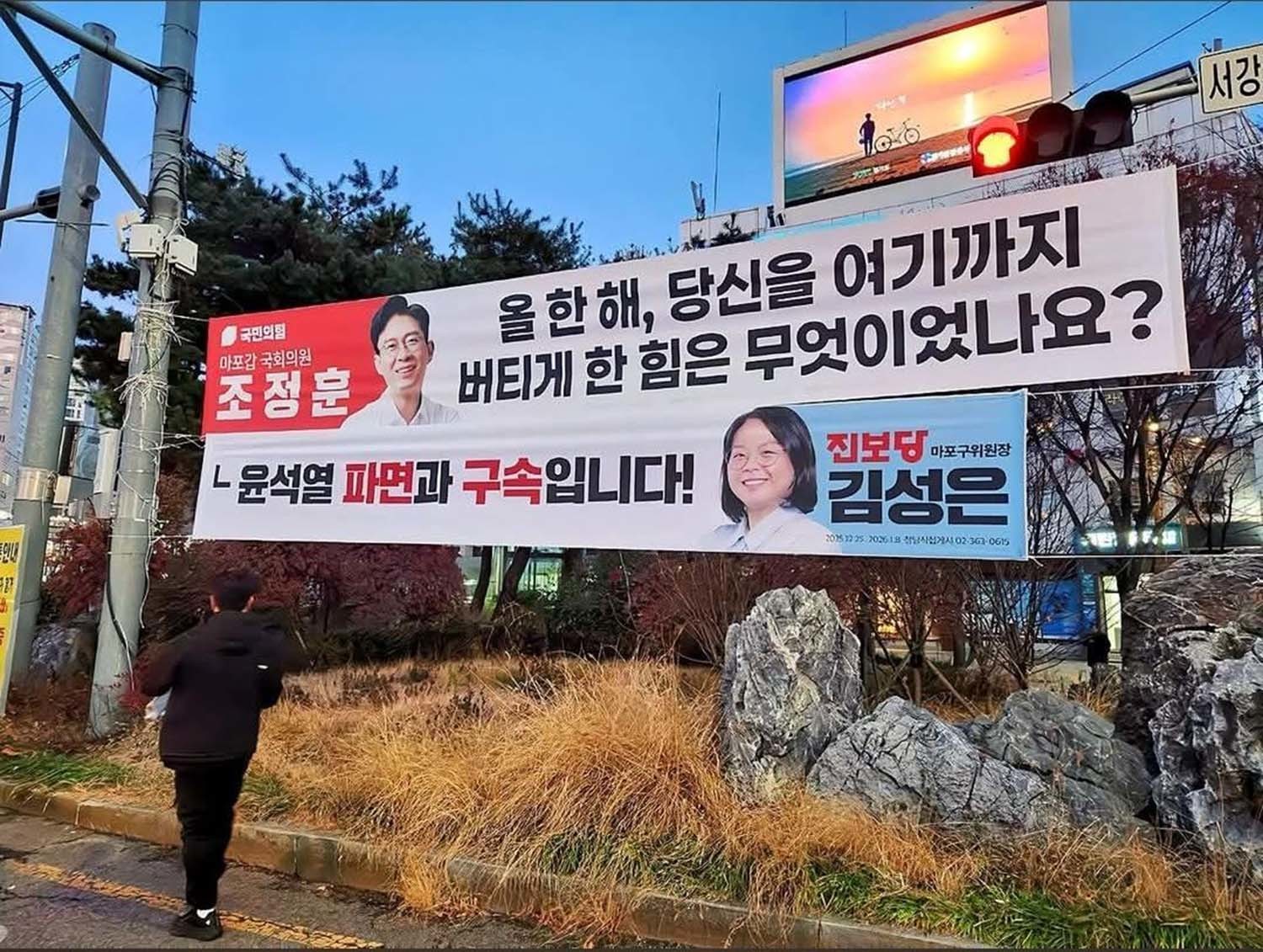 조정훈 국민의힘 의원(마포갑)이 지역구에 ‘올 한 해, 당신을 여기까지 버티게 한 힘은 무엇이었나요?’라고 적은 플래카드를 내걸었어. 그러자 김성은 진보당 마포구위원장이 ‘윤석열 파면과 구속입니다!’라고 적은 플래카드를 바로 아래에 대답하듯이 내걸었다. / 보배드림