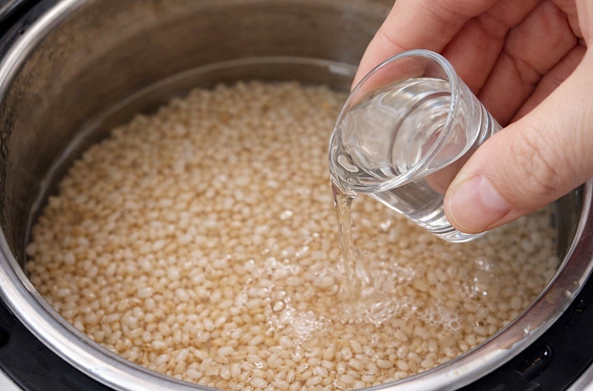 전기밥솥에 있는 쌀에 소주를 붓고 있는 모습. 기사 이해를 돕기 위한 자료 사진입니다. 실제 모습과 다소 차이가 있을 수 있습니다.