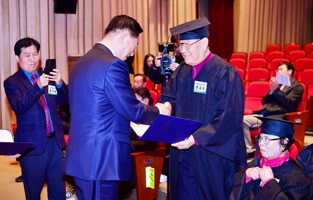 김한종 장성군수가 성인문해교실 수료증을 전달하며 축하 인사를 나누고 있다. 장성군 제공