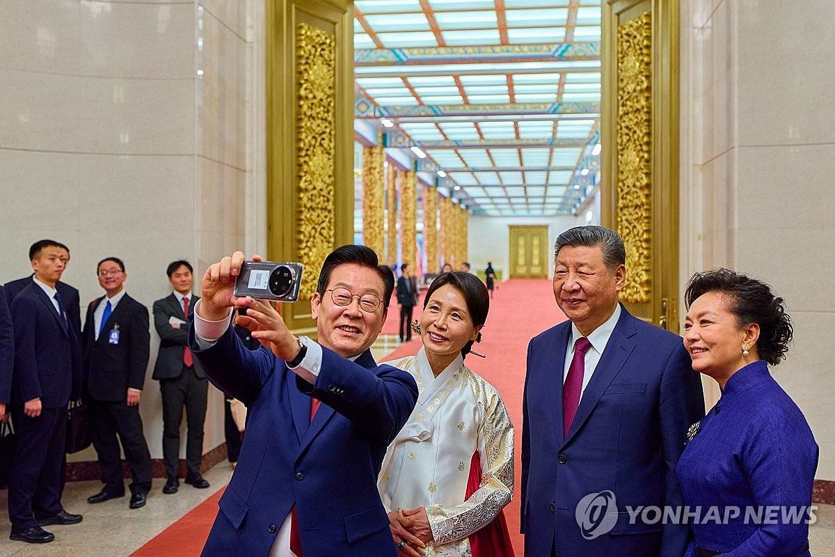 이재명 대통령 부부와 시진핑 국가주석 부부가 지난 5일 중국 베이징 인민대회당에서 국빈만찬 후 샤오미폰으로 기념촬영을 하고 있다. 이 샤오미폰은 경주 정상회담 때 시 주석이 이 대통령에게 선물한 것이다 / 연합뉴스