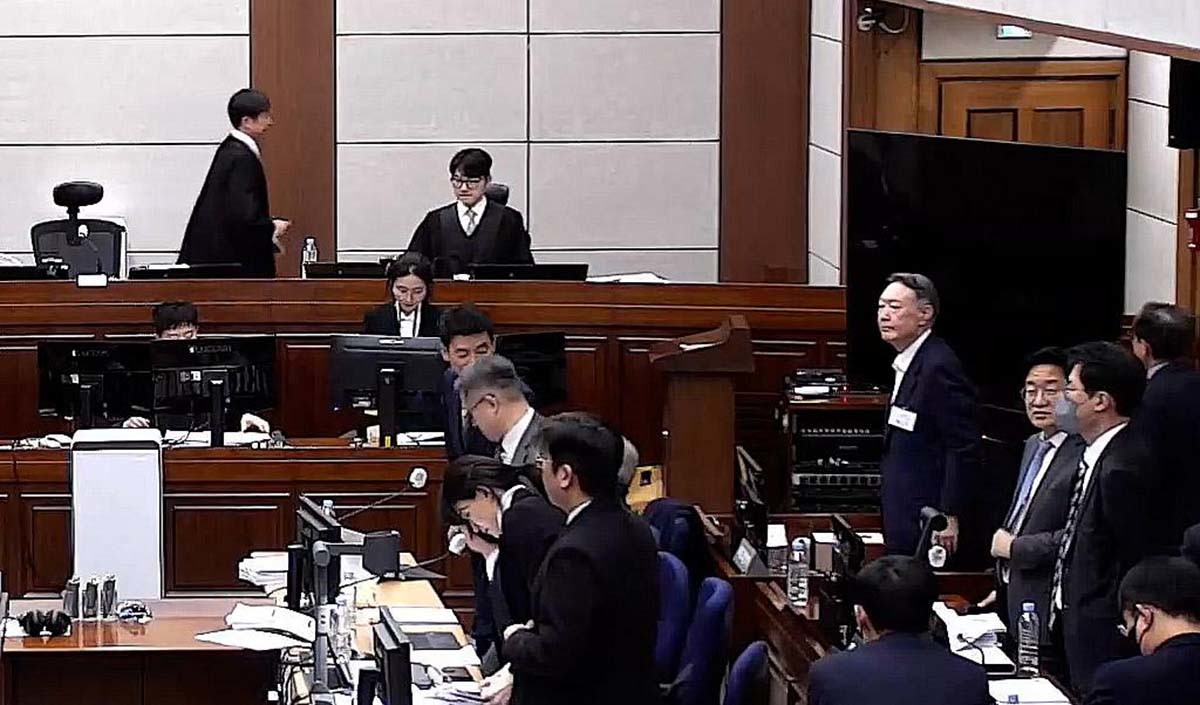 윤석열 전 대통령이 9일 오후 서울 서초구 서울중앙지방법원에서 열린 내란 우두머리 혐의 1심 결심 공판에 출석해 얼굴을 만지고 있다. 윤 전 대통령 앞에는 김용현 전 국방부 장관이 앉아 있다. / 서울중앙지방법원 제공 영상 캡처